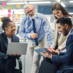 A diverse group of business professionals collaborating in a bright office, discussing ideas and smiling during a meeting